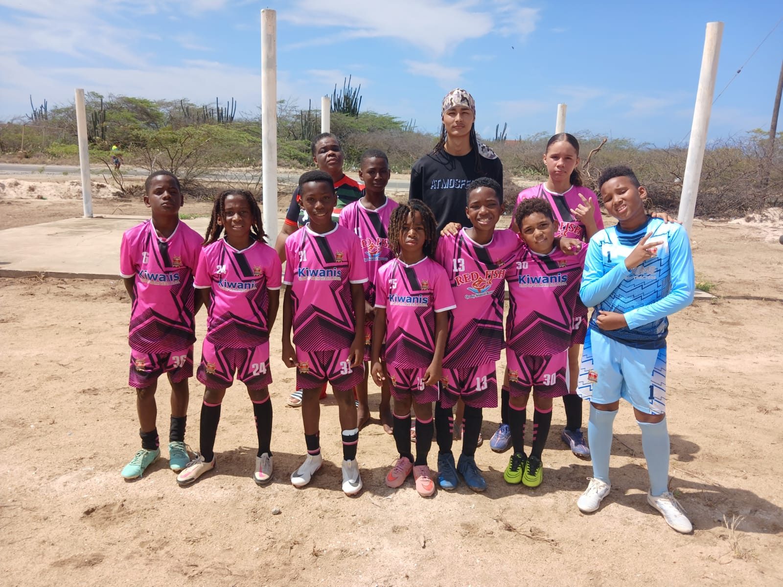 The RCS U13 squad in pink kit with their goalkeeper and coaches